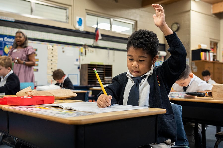 A student in St. Peter's Catholic School raises their hand in class.