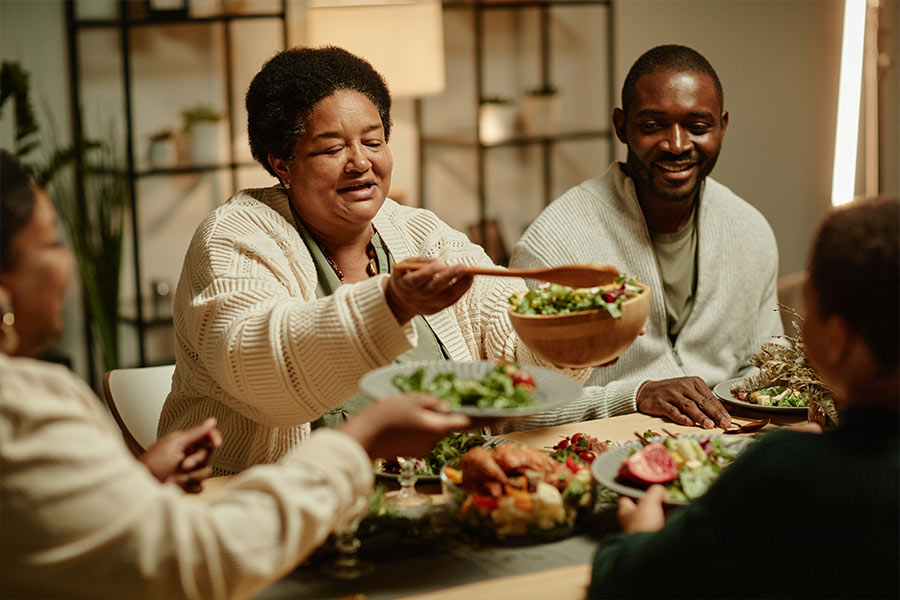 Portrait of smiling African-American grandmother serving food while celebrating Thanksgiving with big happy family at dinner table (iStock)