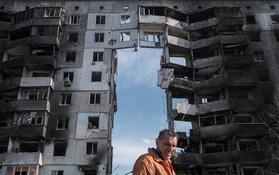 A clean up worker walks past buildings that were destroyed by Russian shelling in Borodyanka, Ukraine, near Kyiv, April 7, 2022.