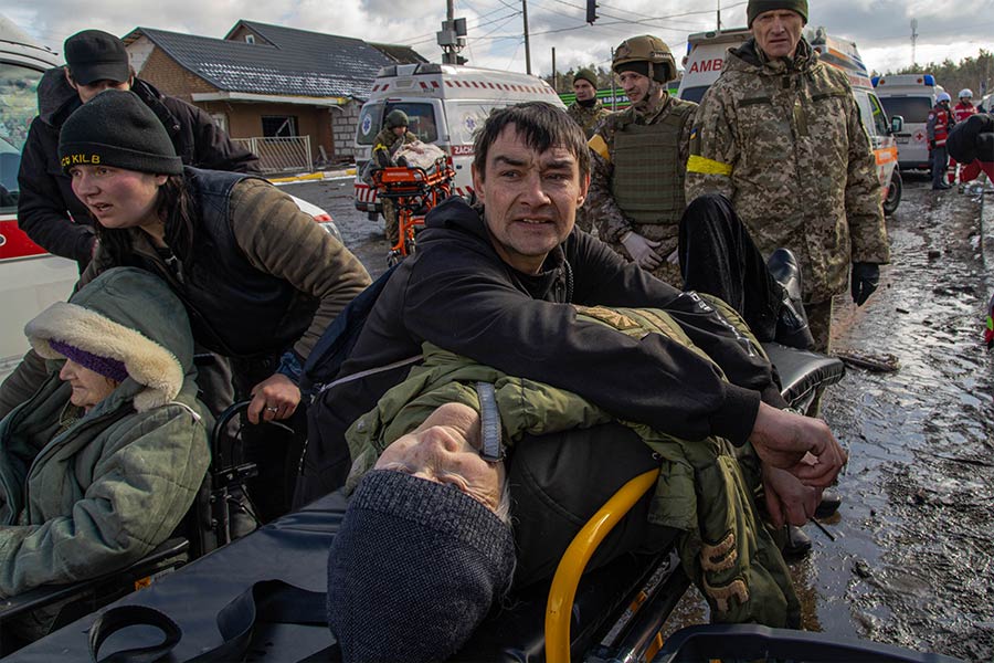 A Ukrainian man comforts his father as they evacuate across the Irpin River in March 2022.