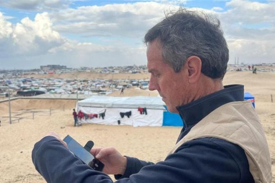 The Catholic Relief Service CEO checks his phone in a desert environment