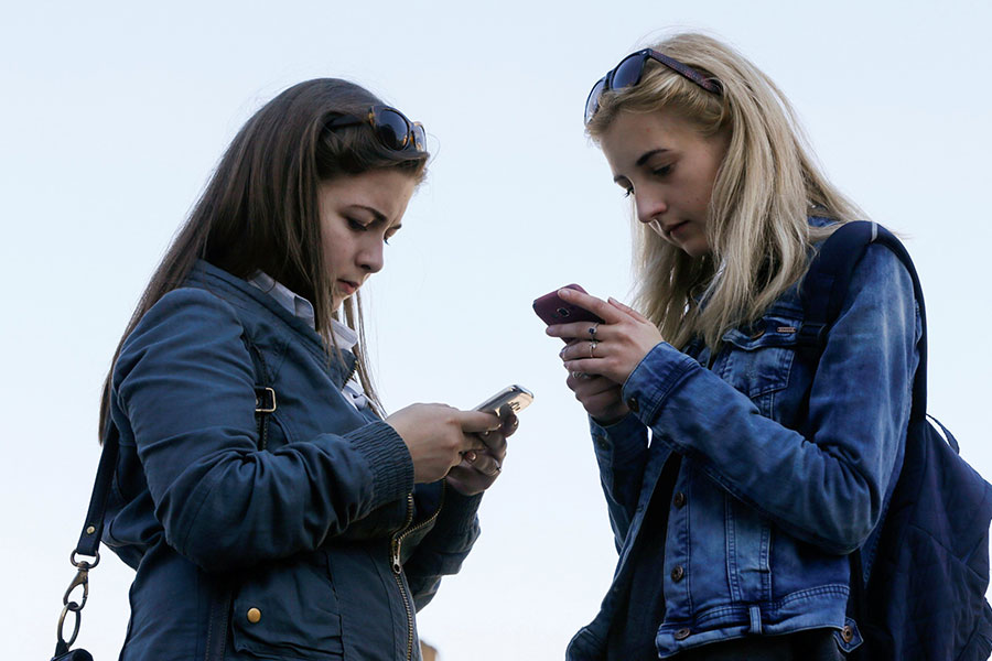Young women are pictured in a file photo using their using their smartphones. 