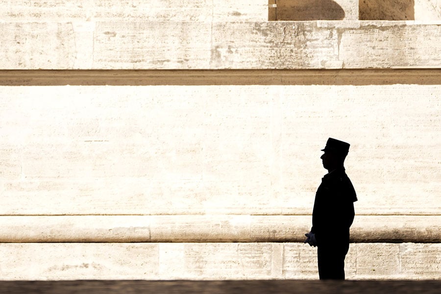 A member of the Vatican gendarmerie, or police force, stands guard as sunlight casts sharp contrasts along a wall near St. Peter’s Square before Pope Leo XIV’s weekly general audience at the Vatican Nov. 5, 2025. (CNS photo/Lola Gomez)
