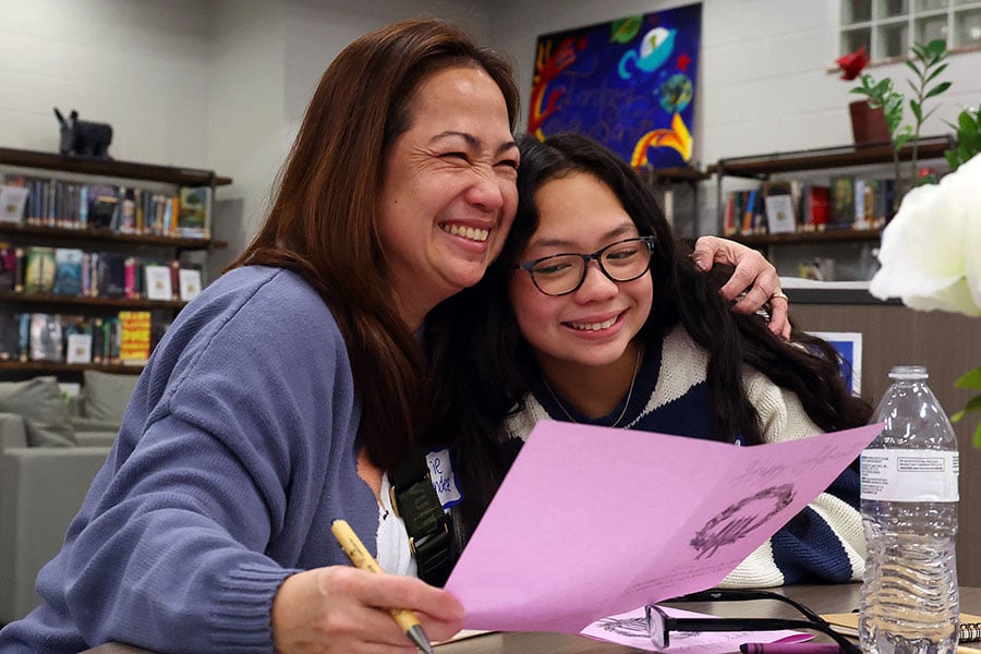 A mother and daughter smile and embrace