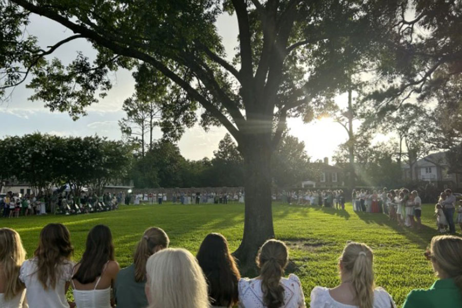 Girls rest heads on each other, bowed before tree