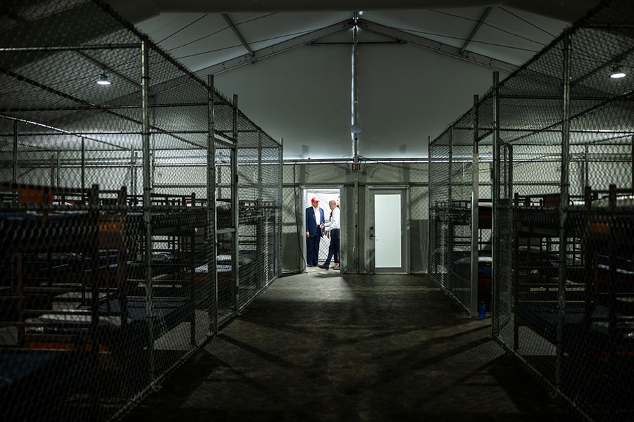 gated bunk beds in a dark warehouse, door open