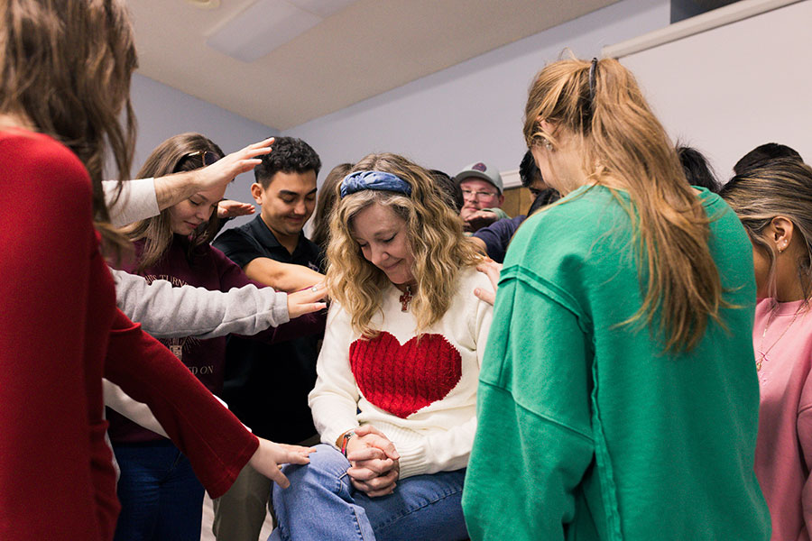 Students at Midwestern State University Catholic Campus Center enjoy a lighthearted moment before they pray a blessing over Debbie Veitenheimer, campus minister. The MSU CCC building opened 40 years ago, and Veitenheimer has served 25 years. (NTC/Bertha Salazar)