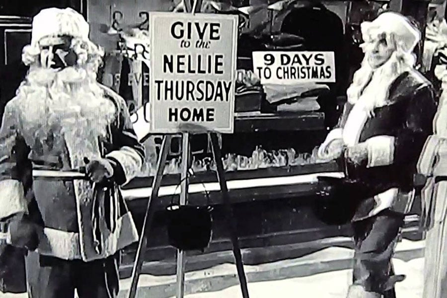 black and white still depicting two Santas asking for donations