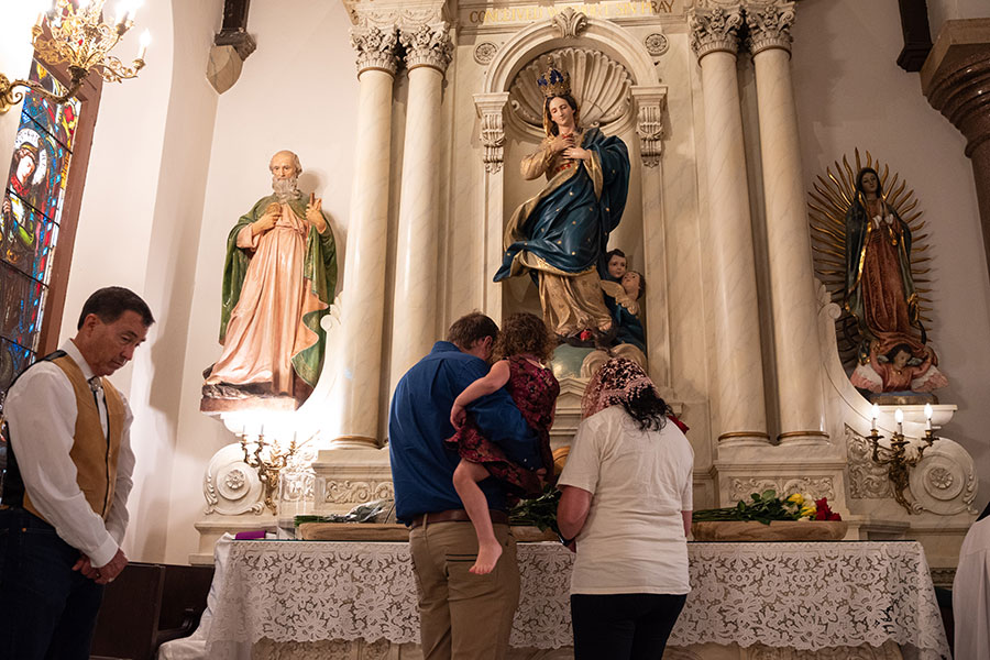 Family drops off flowers in front of statue of Mary