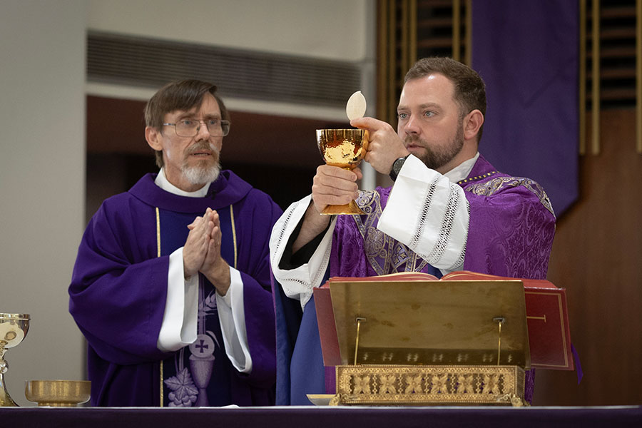 Dcn. David Kinch prays as Fr. Brett Metzler elevates the Eucharist while celebrating the second annual Purple Mass for TCU students and alumni at Holy Family Catholic Church, Saturday, March 7, 2026. (NTC/Rodger Mallison)