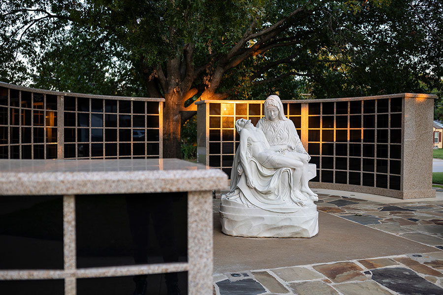 Pieta statue in front of sunlit columbariam