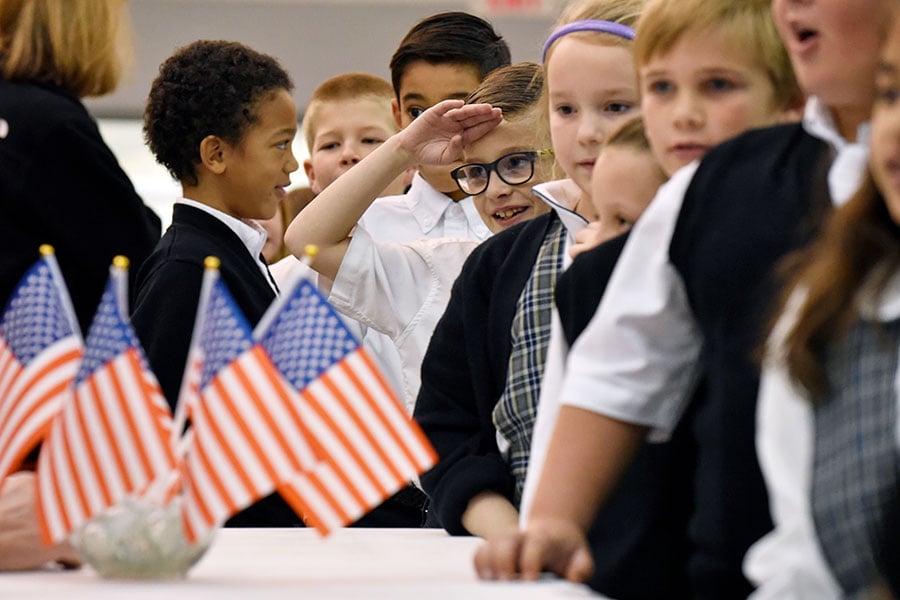 amongst US flags, one boy salutes a veteran 