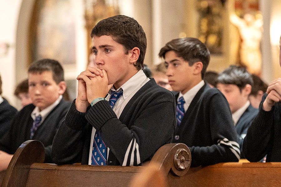 school boys pray during Mass