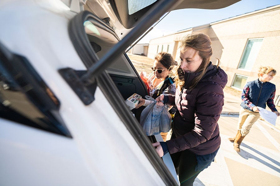 Two women unload groceries from a car