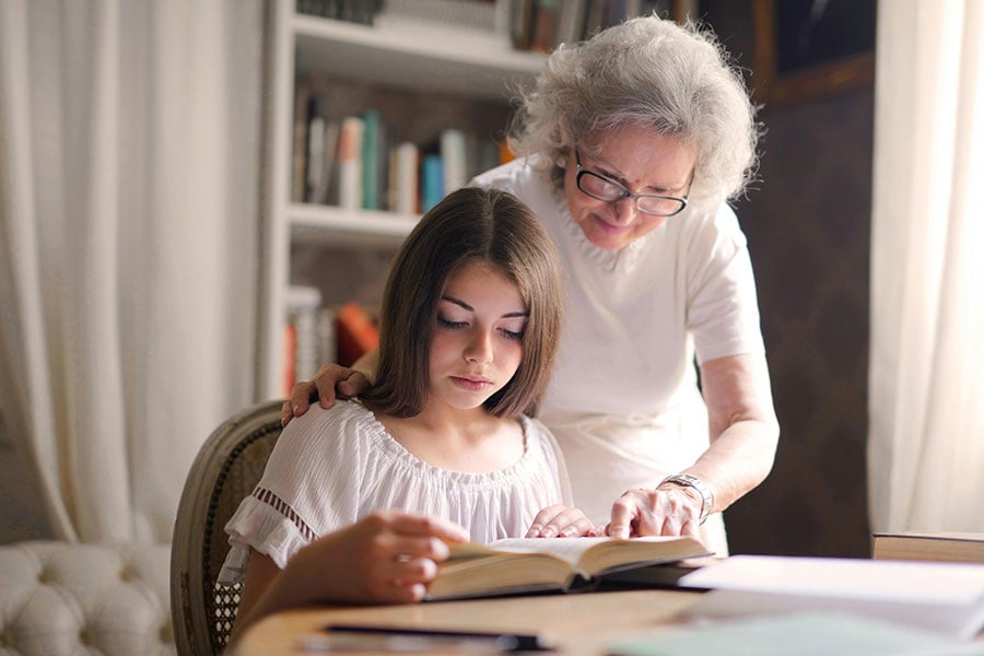 An older woman reading Bible with a teenage girl