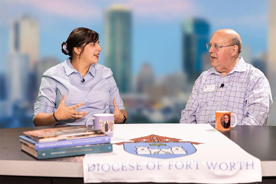 Two podcast hosts speak in a news studio
