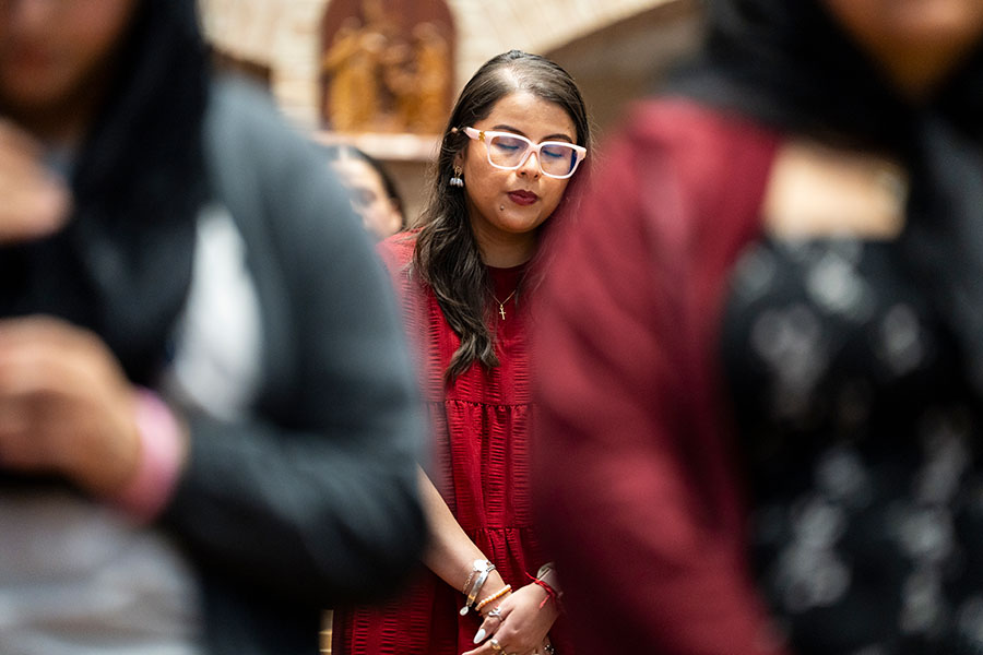 a young woman in red prays in the midst of the crowd during Mass
